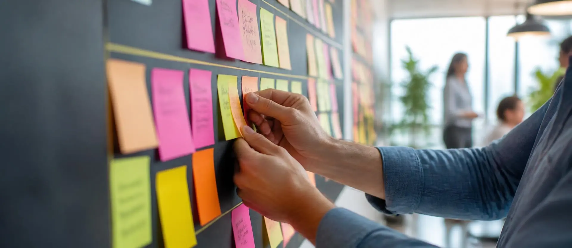 Chef de projet organisant un tableau kanban de post-it sur un mur